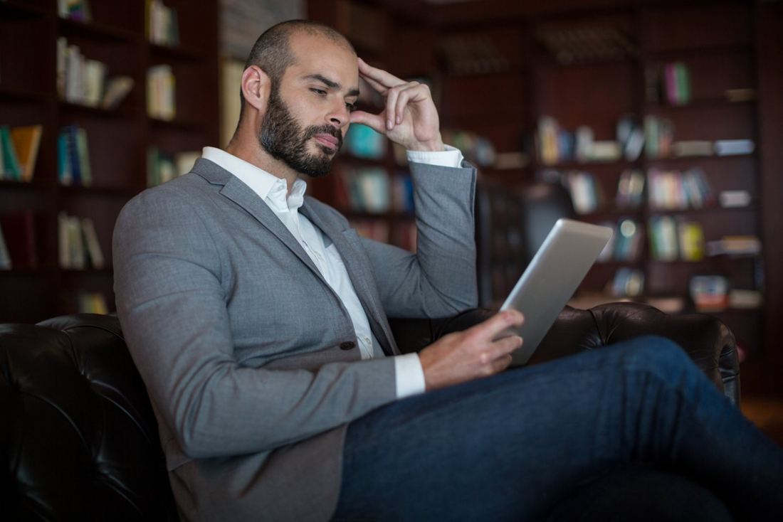 Homem de terno com tablet em uma biblioteca