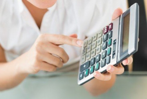 Mão fazendo contas em uma calculadora